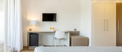 A hotel room with a bed, a desk with a chair, a television, and a wardrobe.
