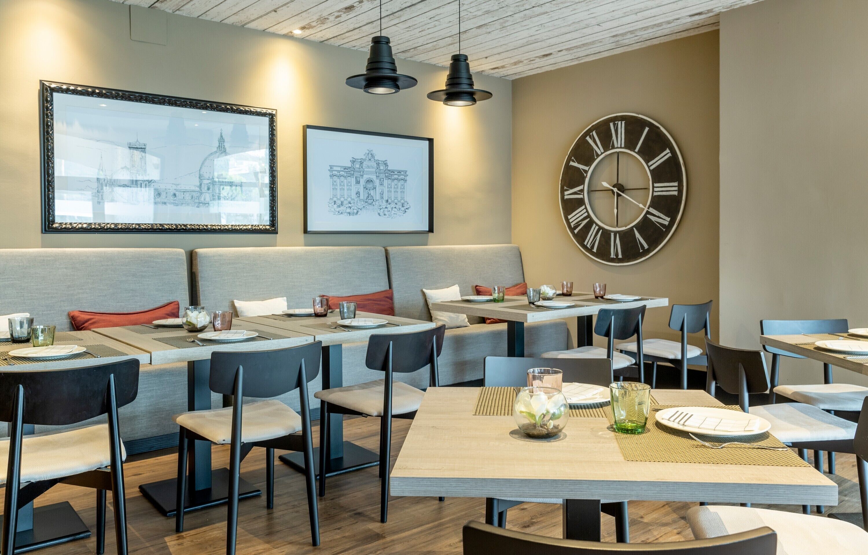 Un restaurante con cabinas y mesas, obras de arte enmarcadas en la pared y un gran reloj.