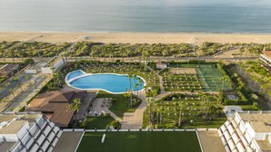 An aerial view of a resort with a swimming pool, a tennis court, and a beach. - Hotel ILUNION Islantilla (Islantilla)