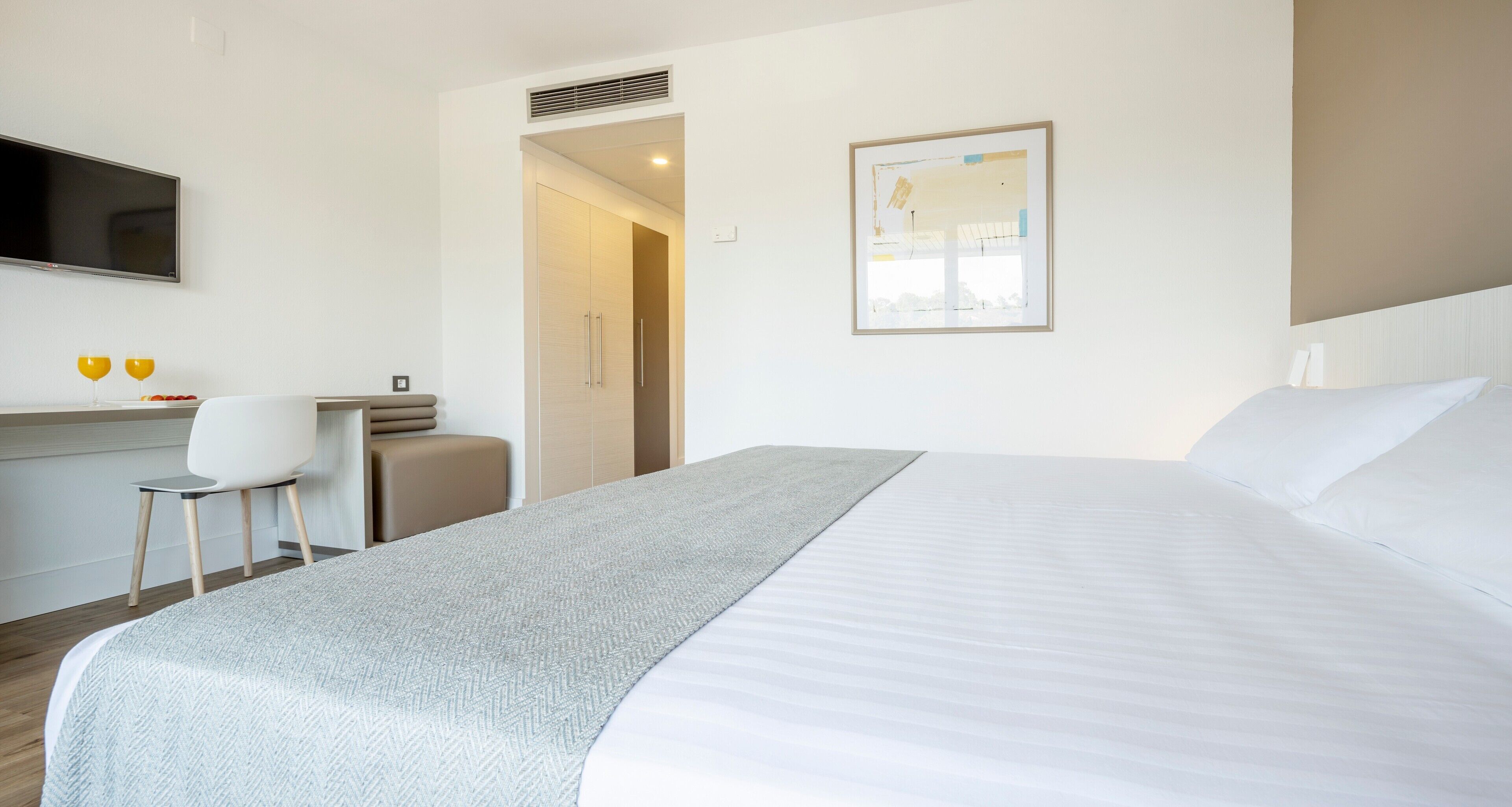 Una habitación de hotel con una cama, un escritorio, una silla, un televisor y una puerta que da a un baño.