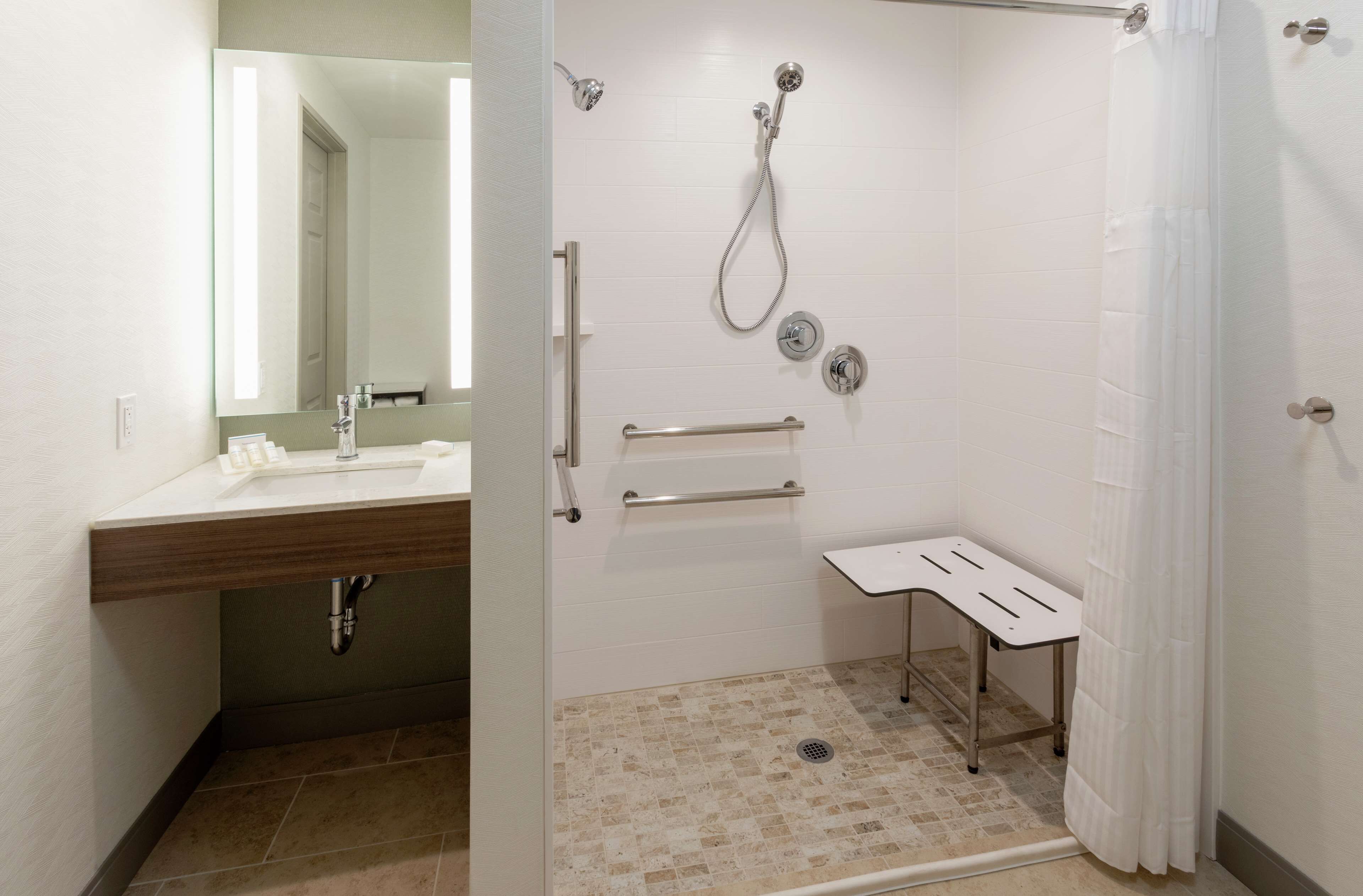 Un baño moderno con ducha, lavamanos y espejo.