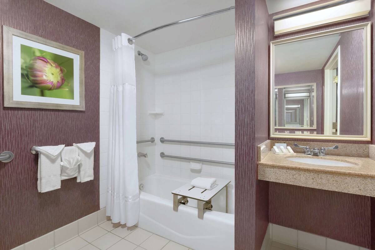 A bathroom with a bathtub, a sink, a mirror, and a shower curtain.