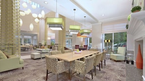 A spacious lobby with a large wooden table, leopard-print chairs, and modern pendant lighting.