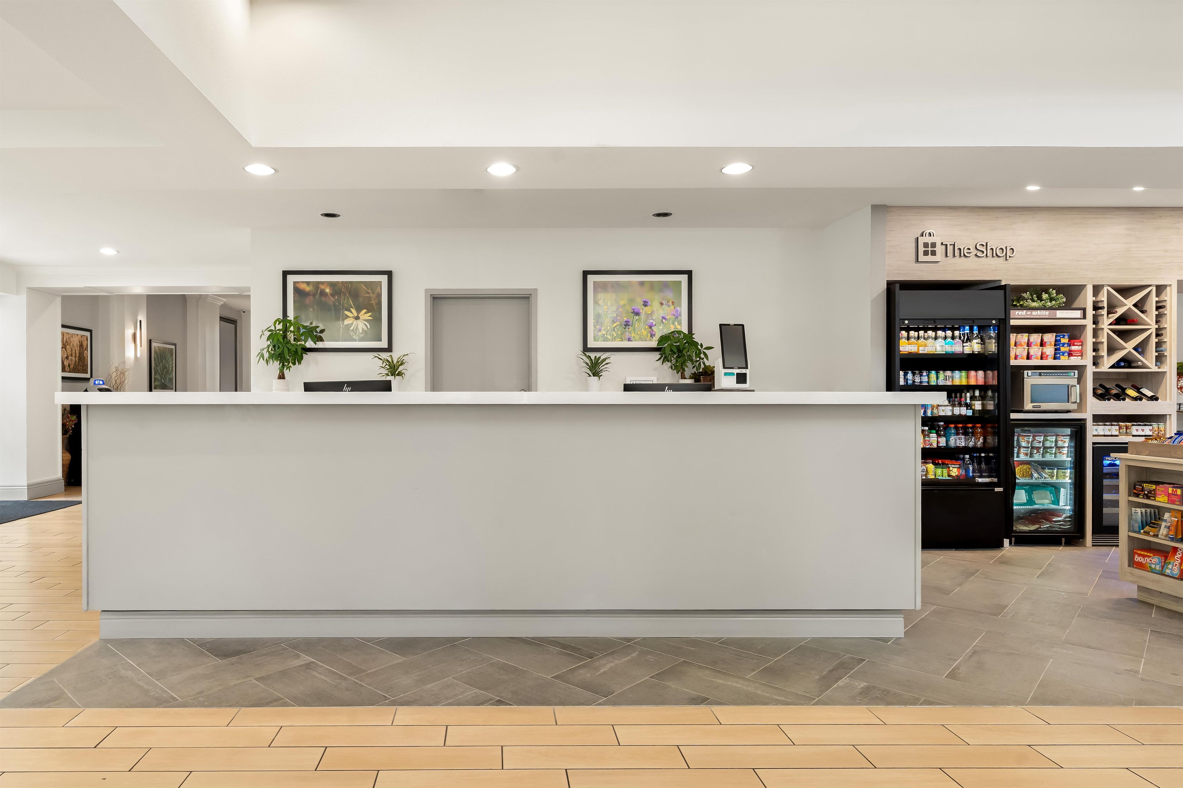 Un comptoir d’accueil au design moderne, un distributeur automatique et un réfrigérateur à boissons en arrière-plan.