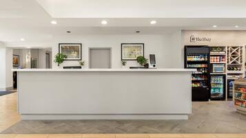 Un comptoir d’accueil au design moderne, un distributeur automatique et un réfrigérateur à boissons en arrière-plan.