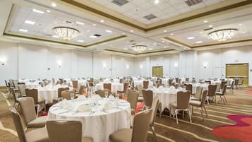 A large banquet hall with round tables set for dining, equipped with chairs and table settings.