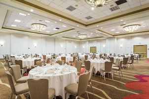 A large banquet hall with round tables set for dining, equipped with chairs and table settings.