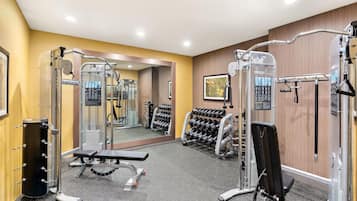 A gym with various exercise equipment, a bench, and a rack of dumbbells.