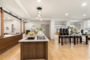 A modern kitchen with a central island, stainless steel appliances, and a variety of food items. - Hilton Garden Inn Fairfield (Fairfield)