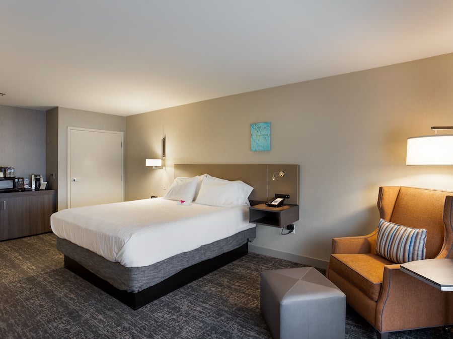 A hotel room with a large bed, a desk, a chair, and a small table.