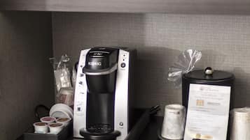 A coffee station with a Keurig coffee maker, a microwave, and a tray with coffee pods and a menu.