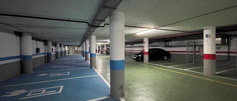 Un parking à plusieurs niveaux avec des voies peintes en bleu et en blanc, des piliers en béton et un sol vert.
