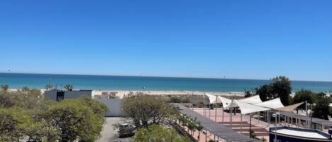 A coastal view with a beach, parking area, and buildings.