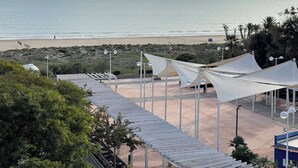 Vista de playa con toldos blancos, arena y mar tranquilo.