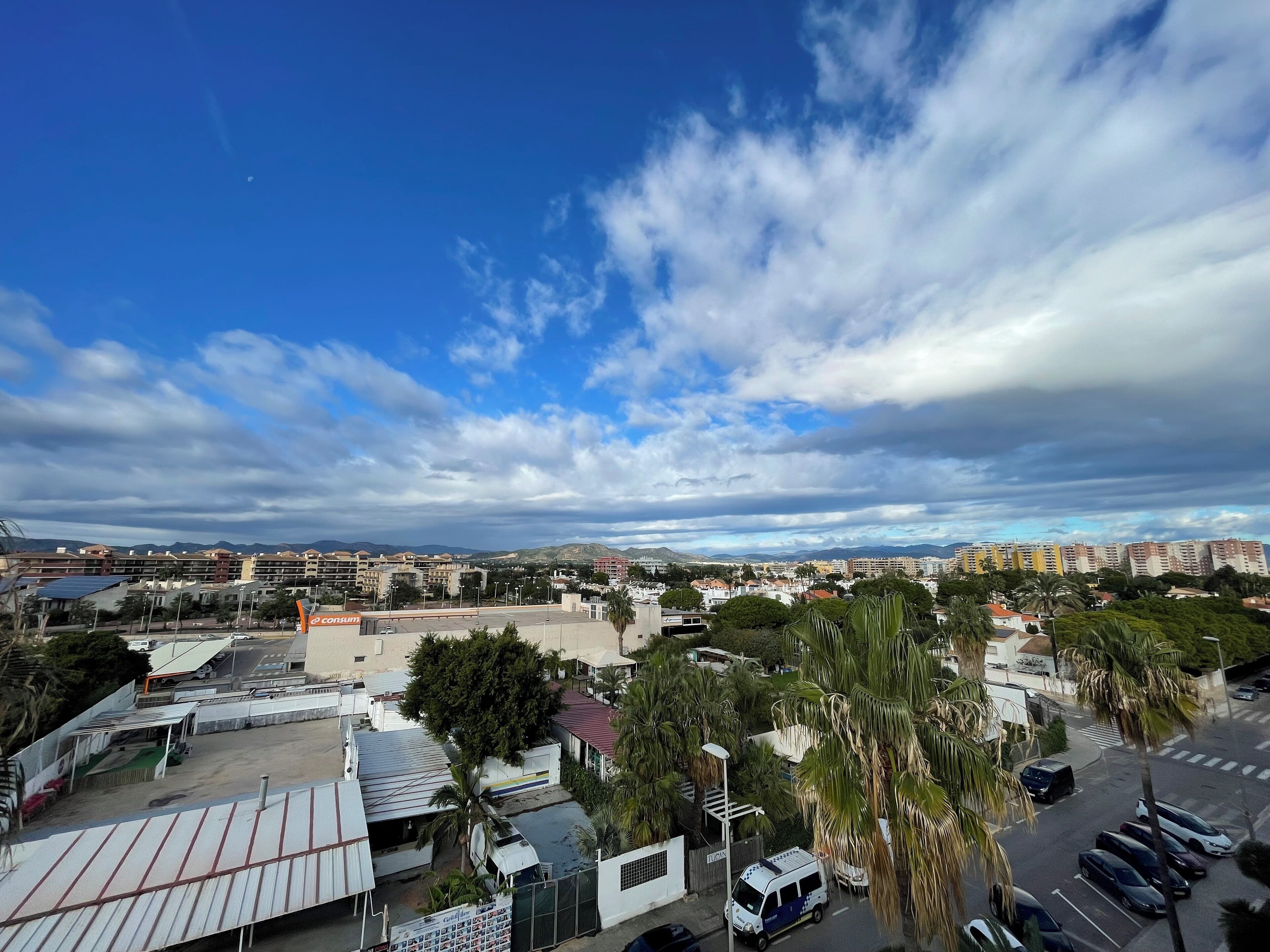 Un paisaje urbano con cielo despejado, edificios y una zona de estacionamiento.