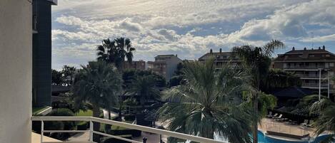 Un hôtel avec une piscine, des palmiers et un ciel dégagé.