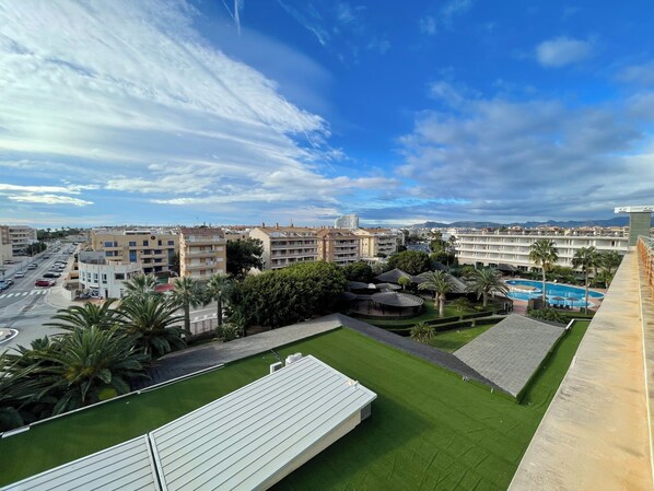 Un hotel con piscina en la azotea, extensas zonas verdes y vistas a la ciudad.