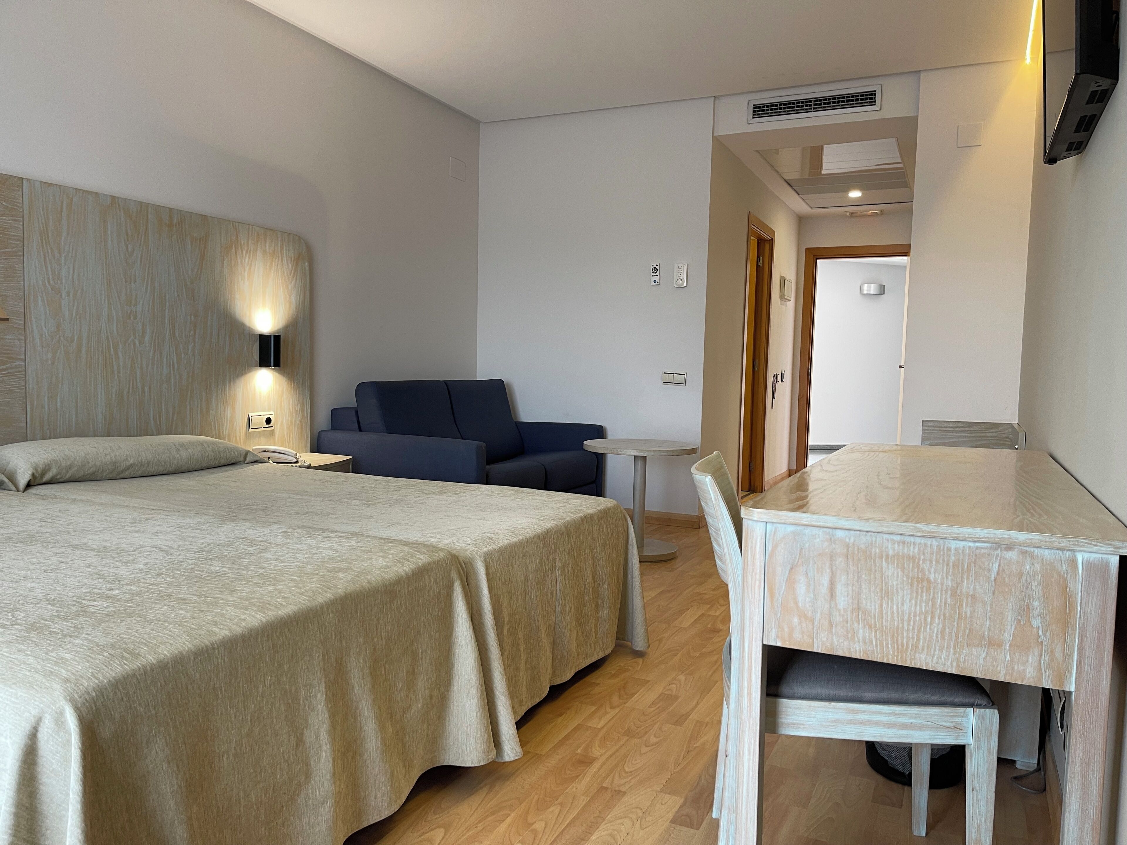 Une chambre d’hôtel avec un lit, un bureau, une chaise, un canapé et une petite table.