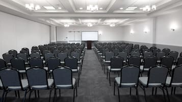 A conference room with rows of chairs, a projector screen, and a podium.