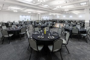 A large conference room with multiple round tables, each set with plates, cutlery, and glasses. - Hilton Garden Inn Grand Forks - UND (Grand Forks)