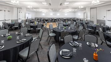 A large conference room with multiple tables set for dining, equipped with chairs and table settings.