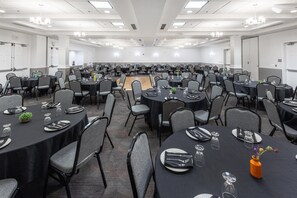 A large conference room with multiple tables set for dining, equipped with chairs and table settings. - Hilton Garden Inn Grand Forks - UND (Grand Forks)