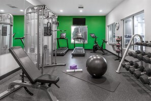 Ein Fitnessstudio mit Cardiogeräten, Kurzhanteln und Rudergerät.
