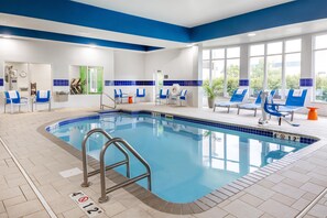 An indoor swimming pool with blue and white tiled walls, a pool ladder, and several lounge chairs. - Hilton Garden Inn Grand Forks - UND (Grand Forks)