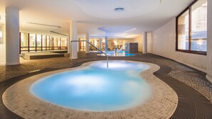 Una piscina interior con borde de azulejos, rodeada de suelo y paredes revestidas con azulejos, con una escalera que lleva a un nivel superior.