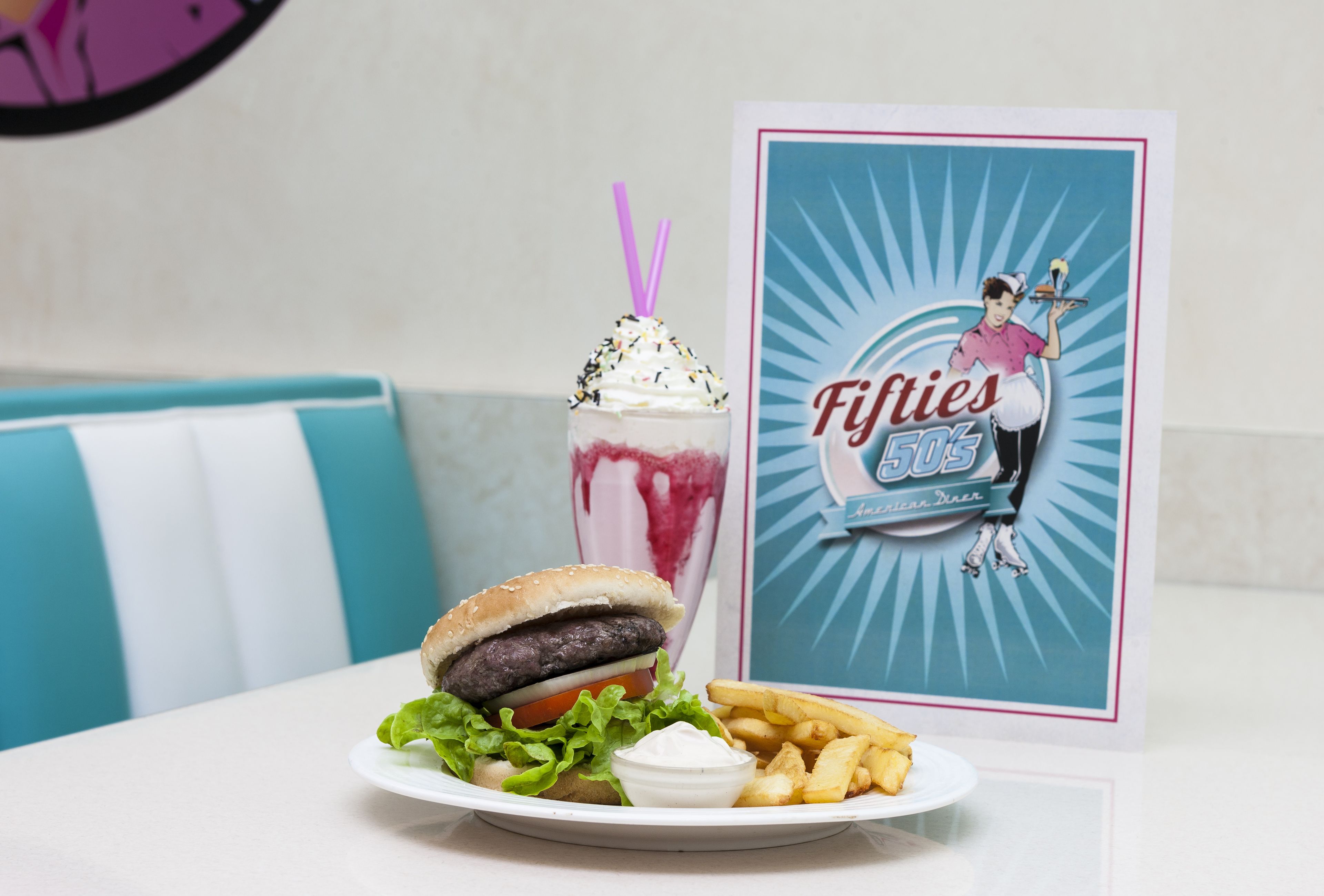 A burger, a milkshake, fries, and a drink on a plate.
