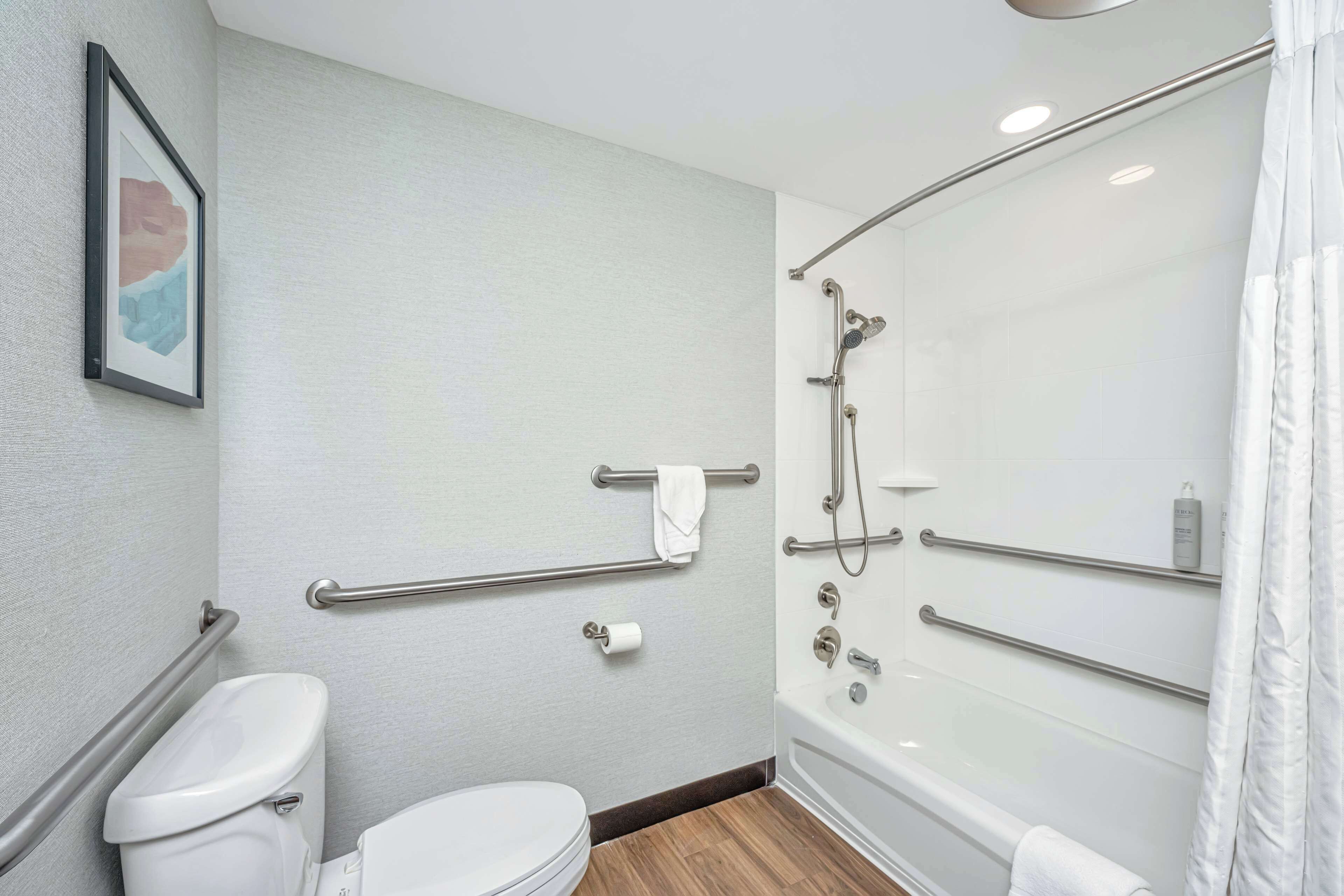 Un baño moderno con inodoro, ducha con mampara de vidrio y un perchero para toallas.