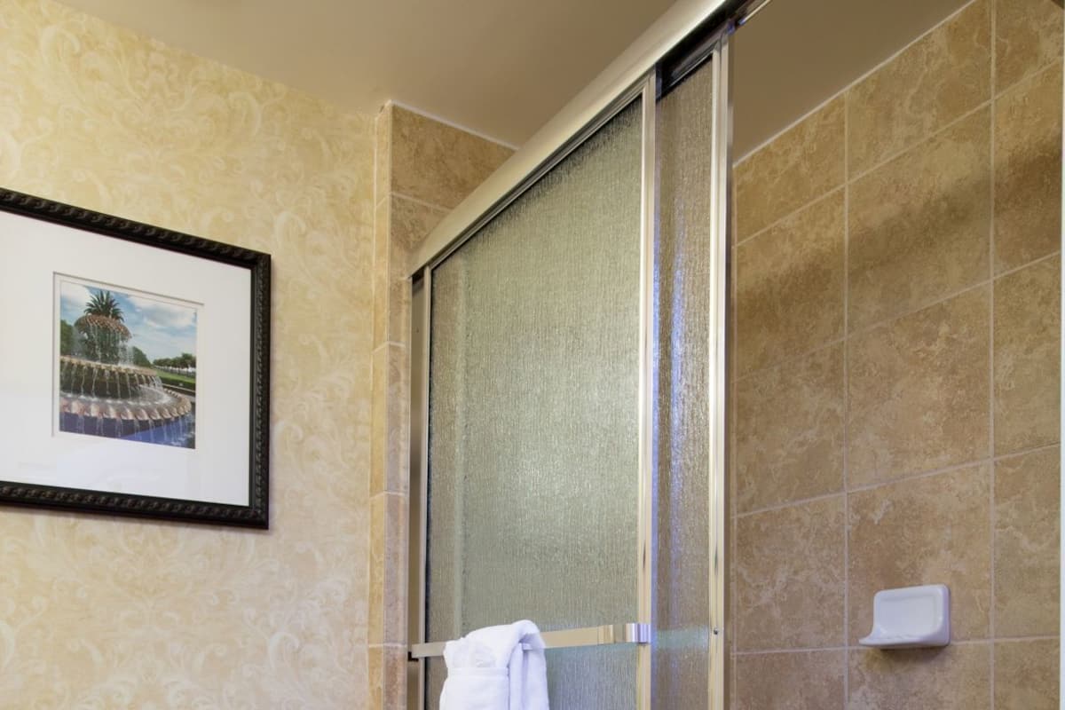 A bathroom with a toilet, a shower with a glass door, and a framed picture on the wall.