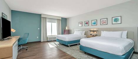 A hotel room with two beds, a desk, a chair, and a TV.