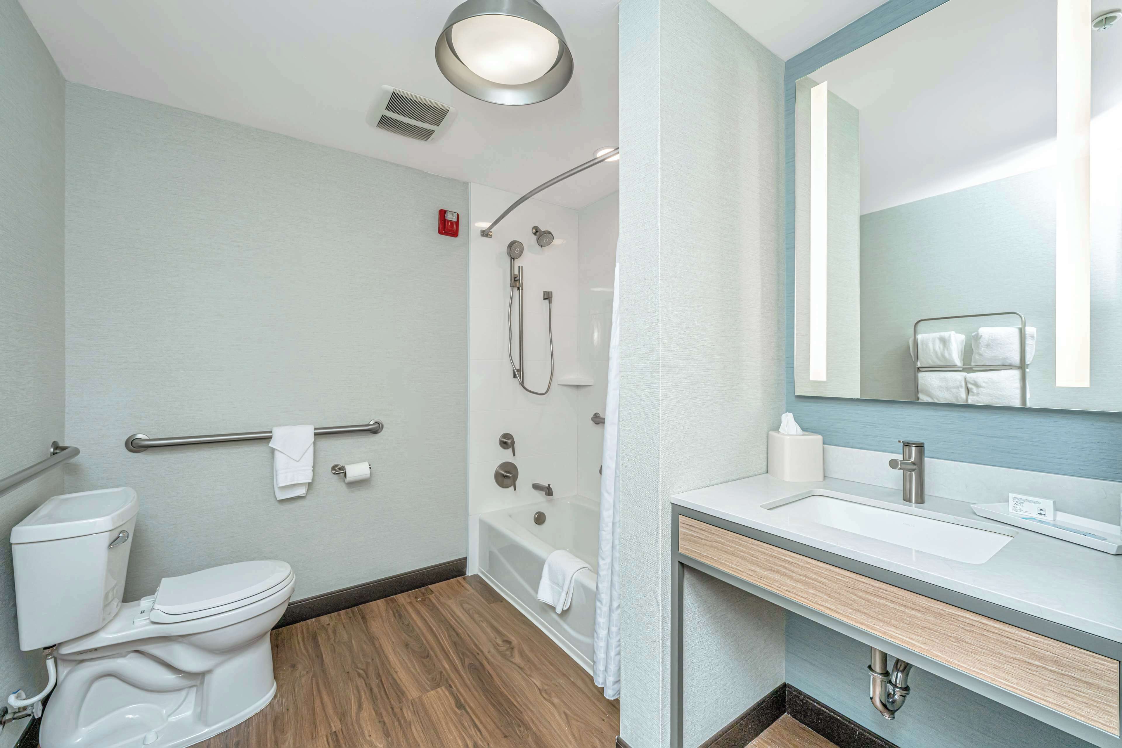 A modern bathroom with a toilet, shower, and sink.