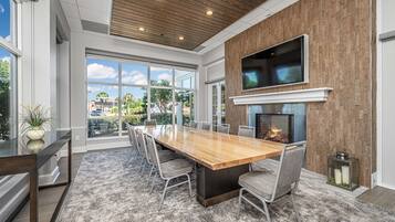 A modern dining area with a large wooden table, comfortable chairs, and a fireplace.