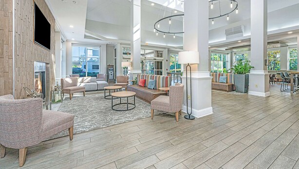 A spacious lobby with a high ceiling, large windows, and a mix of seating areas including sofas and chairs.