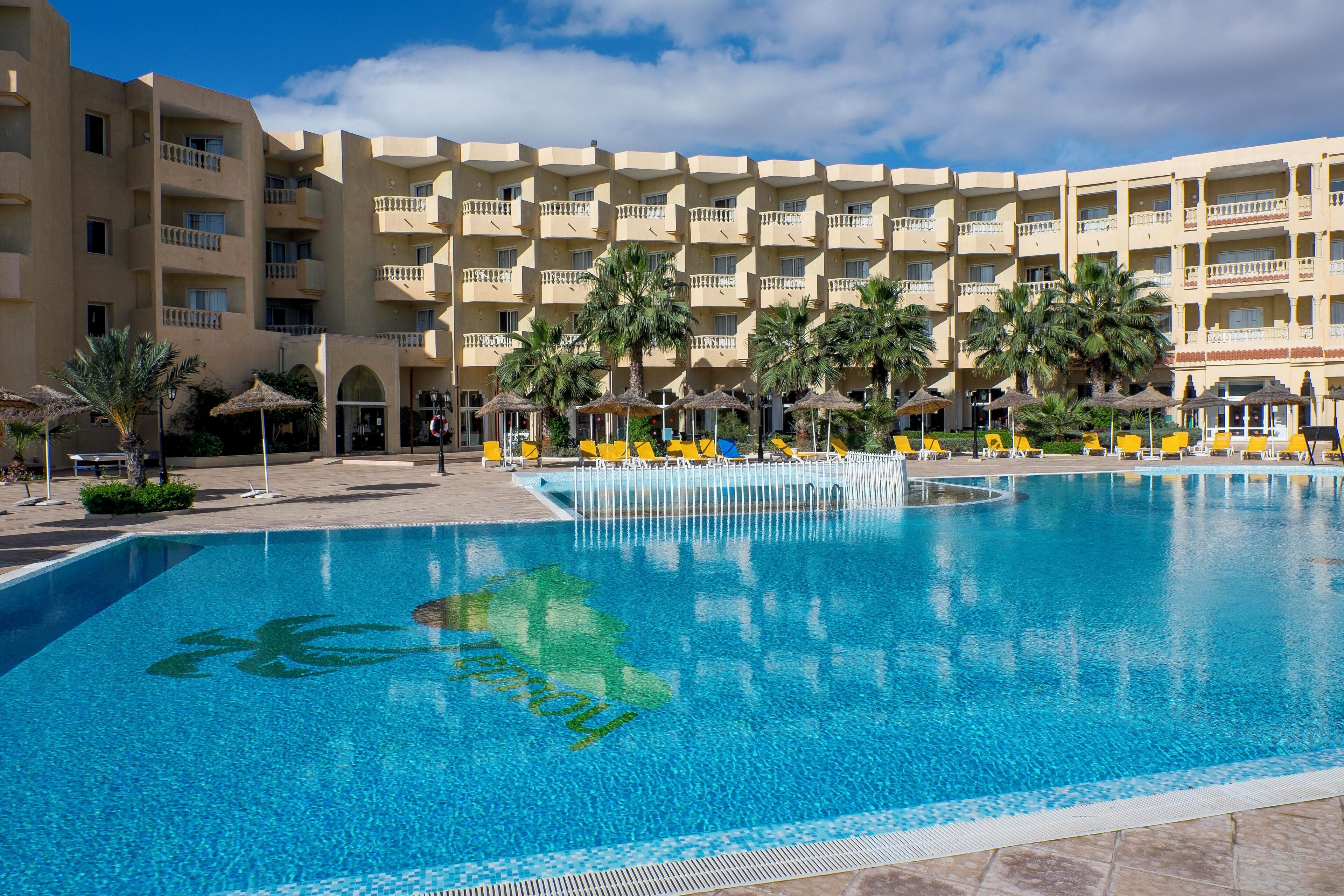 Alberca techada, alberca al aire libre y sombrillas en la alberca