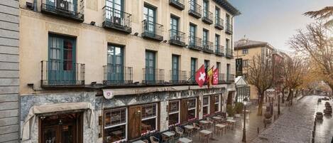 A hotel with outdoor seating, multiple balconies, and flags.