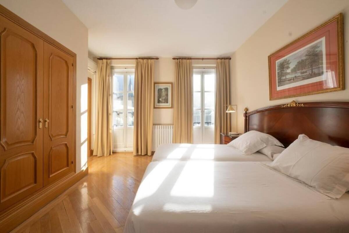 Una habitación de hotel con una cama grande, un armario de madera y un cuadro en la pared.
