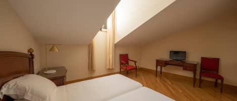 Una habitación de hotel con cama, escritorio, silla, televisión y ventana.