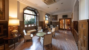 Un vestíbulo amplio con suelo de madera, asientos cómodos y grandes ventanales con vistas al exterior.