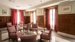 Una sala de reuniones formal con paneles de madera, una mesa de cristal y varias sillas tapizadas.