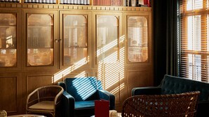 A cozy room with a wooden cabinet displaying bottles, a blue sofa, and a wicker chair.