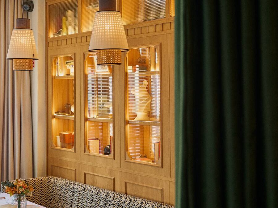 A dining area with a wooden panel wall, hanging pendant lights, and a bench.