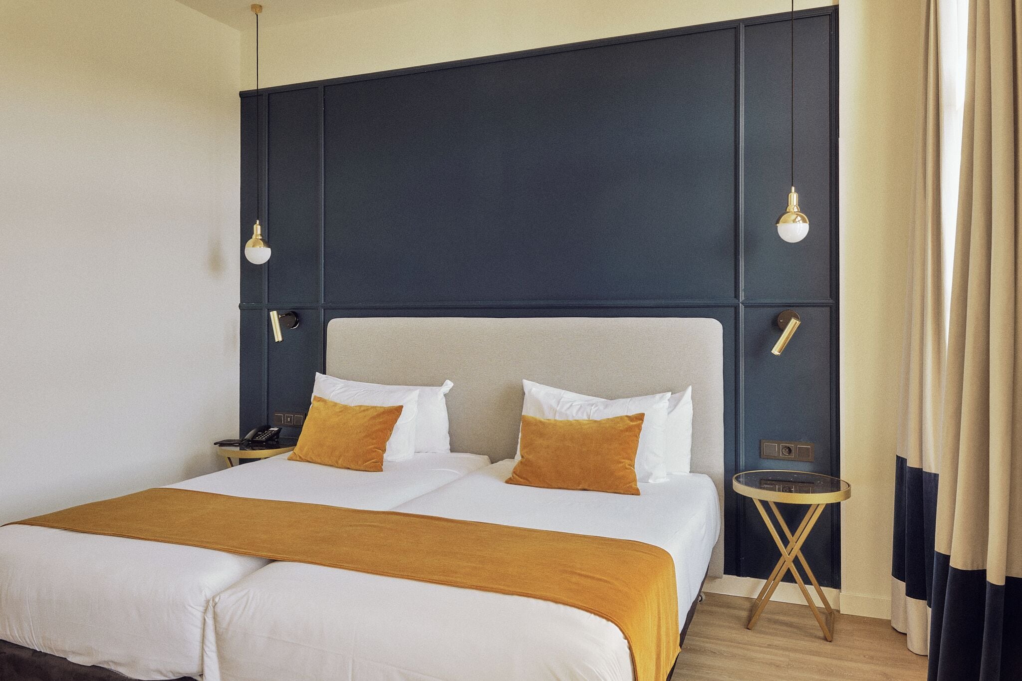 Habitación de hotel con una cama grande, dos mesitas de noche y una lámpara de pared.