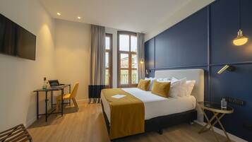 Una habitación de hotel moderna con una cama, un escritorio con una computadora portátil, una silla y una mesita.