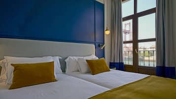 Hotellihuone, jossa on suuri sänky, näkymä rakennustyömaalle ja sininen tehosteseinä.