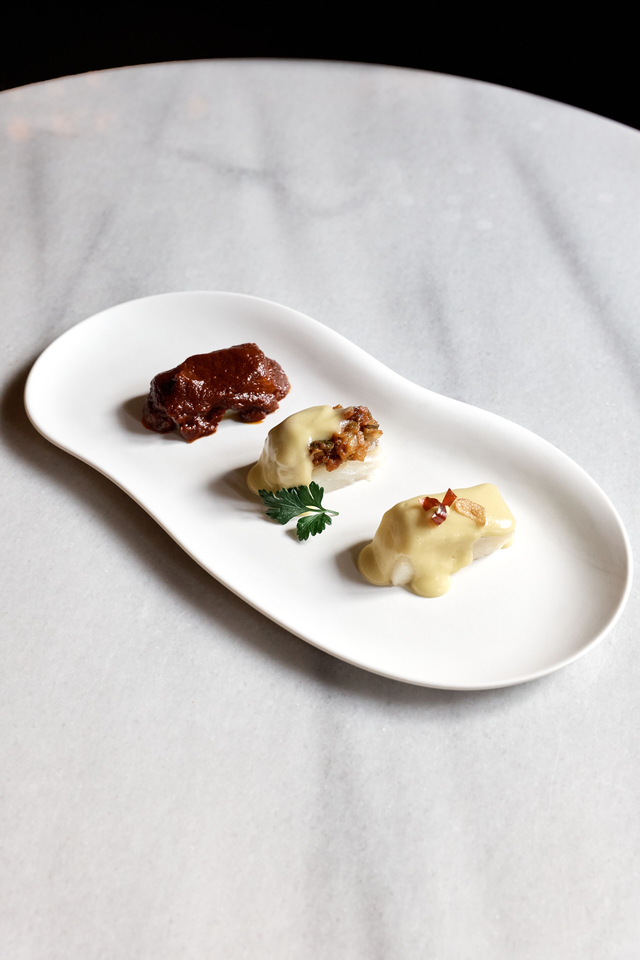 Un plato blanco con tres alimentos sobre una superficie de mármol.