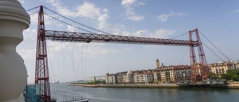 A view of a bridge spanning a river with buildings on the opposite bank.