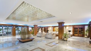 A spacious lobby with a marble floor, a central seating area with sofas, and a piano bar. - Elba Motril Beach & Business Resort (Motril)